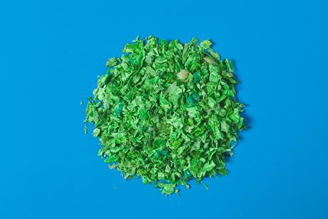 Green plastic recycled polymer parts on blue background